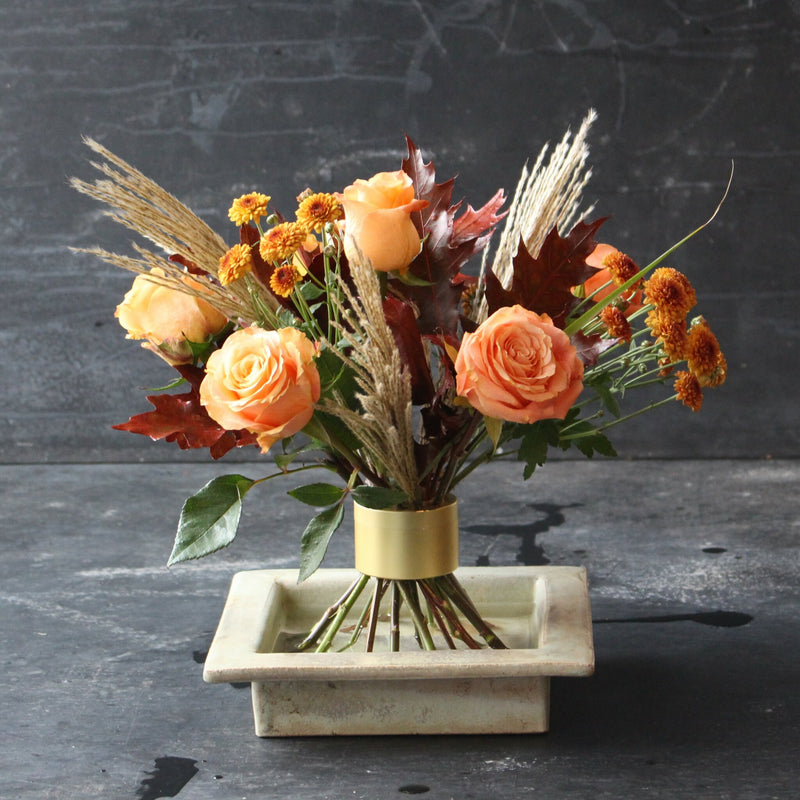 Herfstachtig Ikebana arrangement met oranje rozen en seizoensbladeren met een Hanataba Champagne Gold Spiral Stem houder.