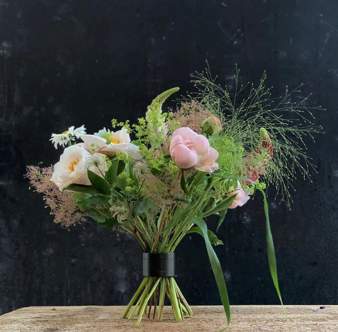 Een delicaat boeket van roze rozen, witte bloemen en pluizig groen, netjes vastgemaakt door een Hanataba Bouquet Twister spiraalvormige steelhouder.