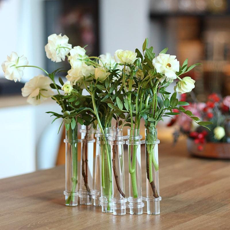 Elegante Flowerflute vaas van Hanataba met een arrangement van verse witte rozen op een houten tafelblad.