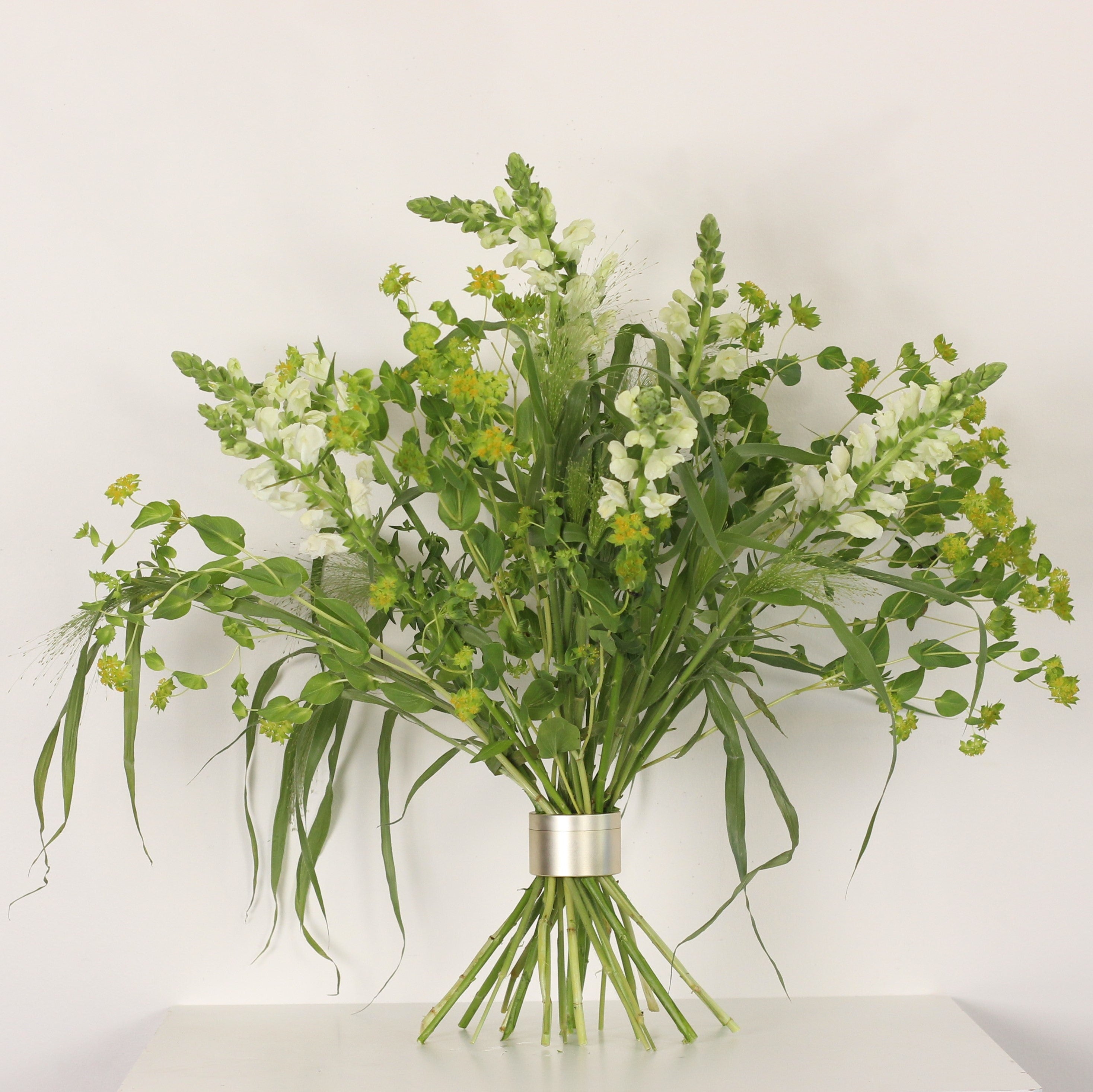 Een op Ikebana geïnspireerd bloemstuk in volle bloei, vastgezet door een Bouquet Twister, met een harmonie van witte en gele bloemen.