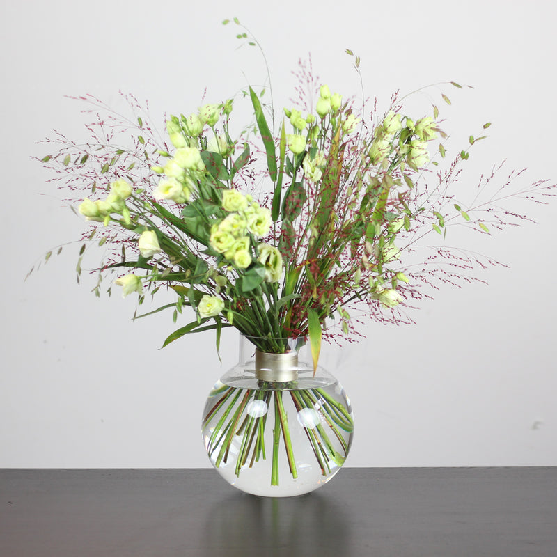 Een bloemenpresentatie in Ikebana-stijl met frisgroene bloemen en delicate roze accenten, kunstig gerangschikt en ondersteund door een Hanataba Spiral Stem-houder