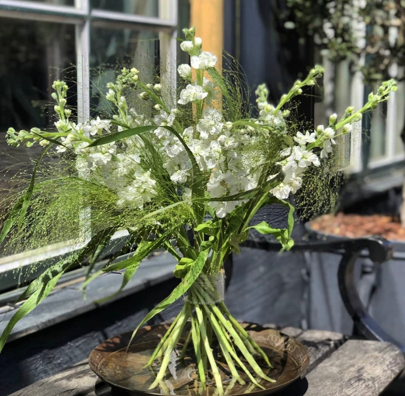 Een Ikebana arrangement met een assortiment delicate witte bloemen, aangevuld met een Hanataba Crystal Clear Spiral Stem Holder voor een modern tintje.