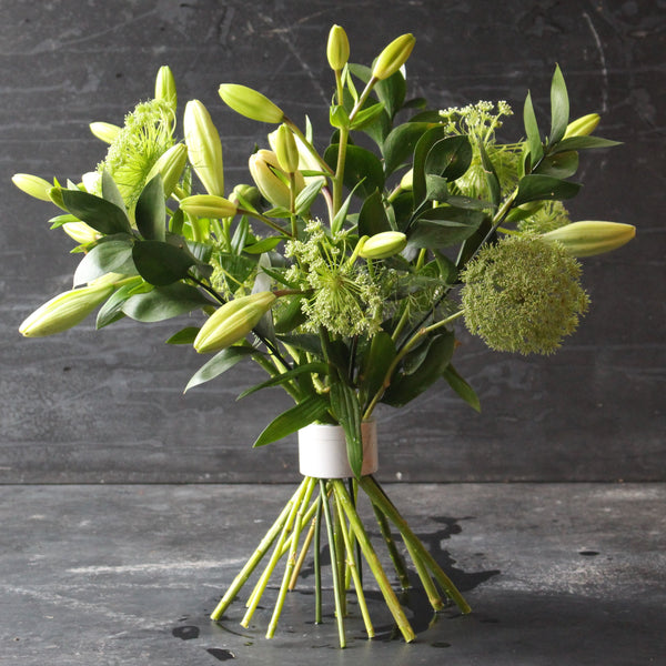 Fris groen en wit bloemenboeket omklemd met een Hanataba Pearly Silver twister tegen een donkere achtergrond.